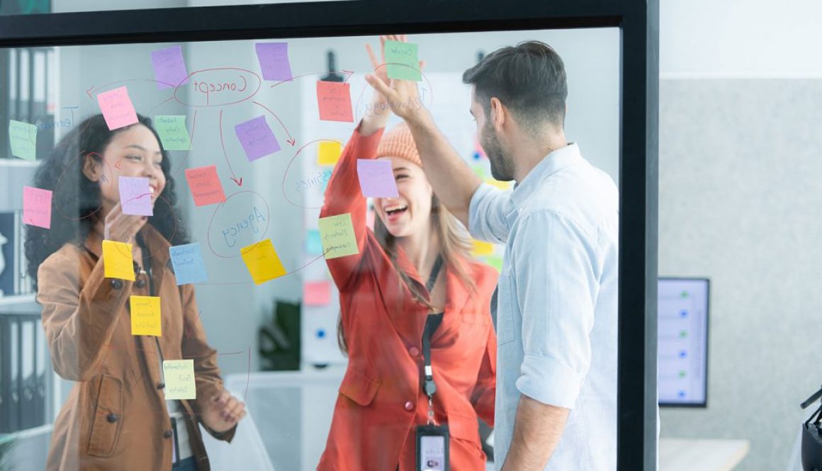 young professionals mapping a process with notes on a clear board