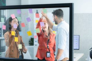 young professionals mapping a process with notes on a clear board