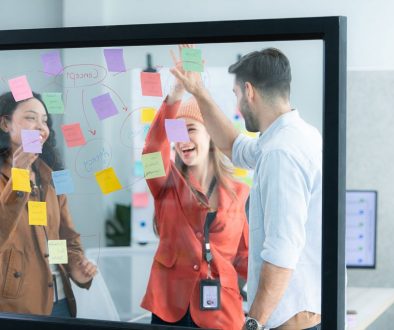 young professionals mapping a process with notes on a clear board