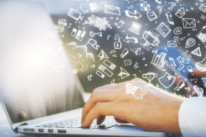 hand typing on laptop keyboard hand drawn icons floating over hand