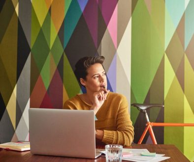 Woman with laptop thinking colorful background