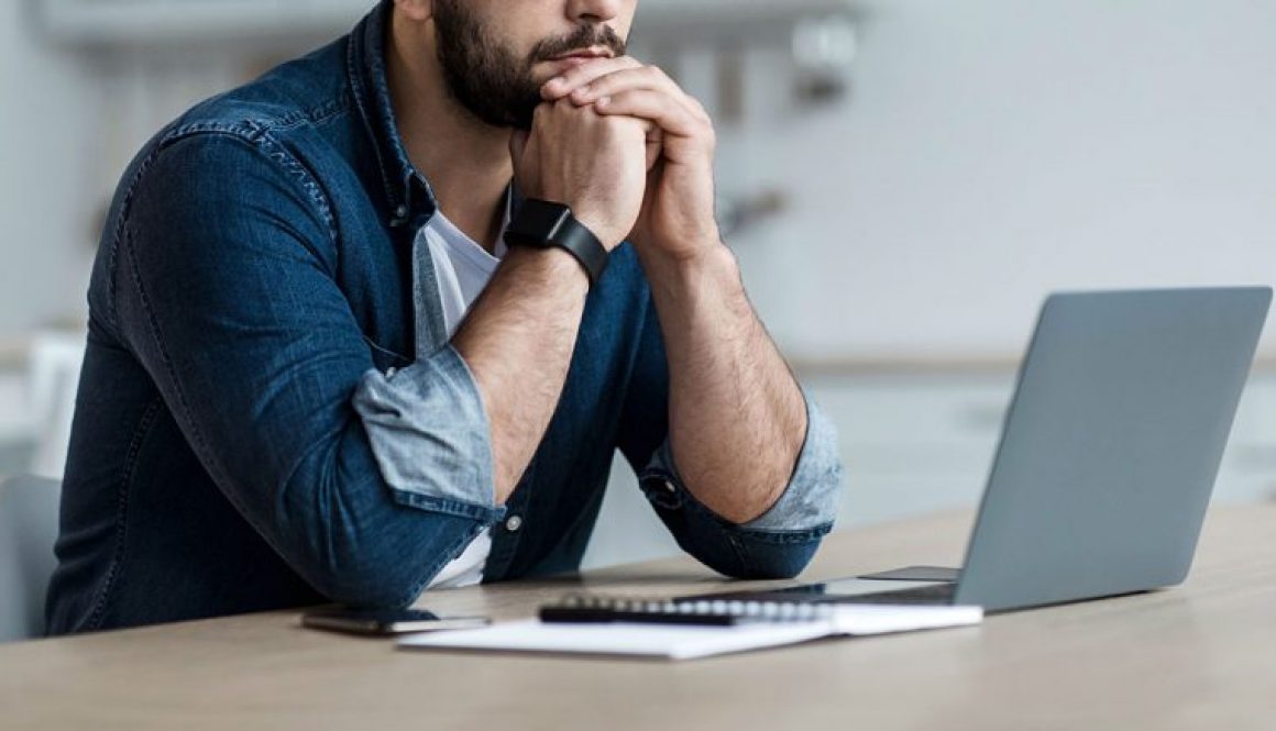 man thinking behind a laptop computer