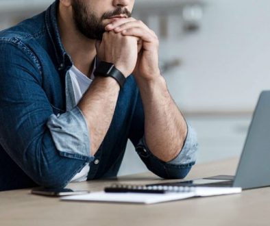 man thinking behind a laptop computer
