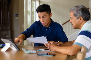Dad and son are discussing business at a table with a tablet